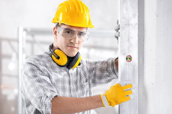 Joven constructor comprobando una pared vertical — Foto de Stock