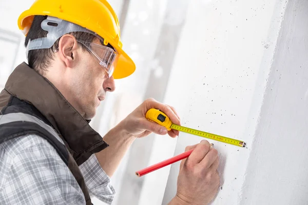 Construtor marcando uma medição com um lápis — Fotografia de Stock