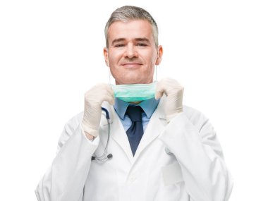Yüzünde cerrahi maske ve eldivenlerle gülümseyen dost canlısı doktor maskeyi indirip beyaz bir korona virüsü ve Covid-19 konseptinde izole edilmiş kameraya gülümsüyor.