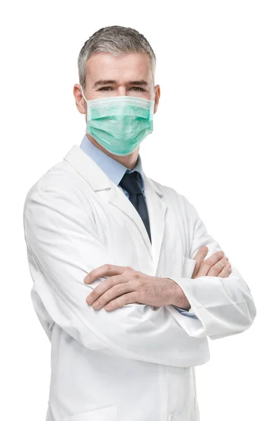 医師は コロナウイルスやCovid 19の概念で白に隔離された研究室のコートに交差腕で立って感染症に対する外科マスクを着用 — ストック写真