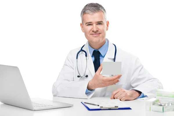 Médico Sonriente Mostrando Una Caja Medicamentos Mano Mientras Sienta Escritorio —  Fotos de Stock