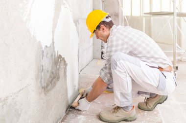 İnşaatçı, tadilat ve tadilat sırasında kapalı bir duvardaki rutubetli lekeyi kapatmak için yüksek tuşlu yakın plan ile yeni alçı uyguluyor.