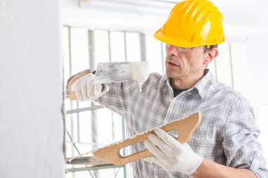 Tadilat sırasında bir evin duvarını sıva ya da inşaatçı sıva ile kaplayan yüksek anahtarlı bir portrede yeni bir yapı inşaatı