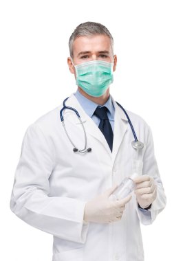 Doktor laboratuvar önlüğü, cerrahi maske ve eldiven takarak korona ya da Covid-19 virüsünden korunmak için elinde el hijyeni için bir şişe dezenfektan tutuyordu.