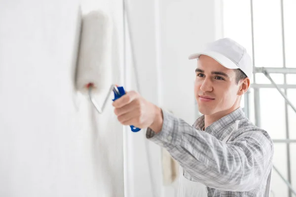 Amistoso Joven Pintor Masculino Pintando Una Pared Blanca Con Rodillo —  Fotos de Stock