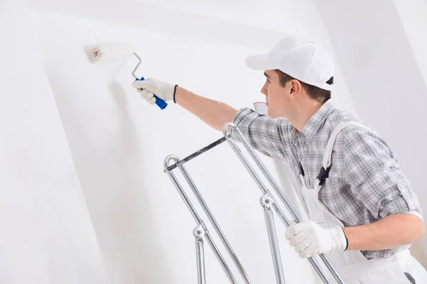 Jovem Pintor Pintando Uma Parede Branca Com Rolo Durante Reformas — Fotografia de Stock