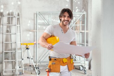 Tebessüm eden müteahhit ya da yönetici, inşaat halindeki yüksek bir odada kameraya gülümseyen bir plan tutuyor.
