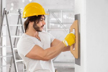 Sıvacı, bina inşaatı sırasında mala kullanarak beyaz bir duvarın yüzeyini tamamlıyor ya da evin içini yeniliyor.