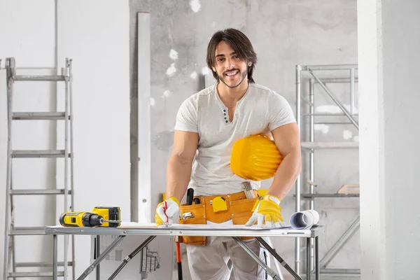 Bina yöneticisi, mühendis ya da mimar inşaat halindeki bir odada duran binanın planı hakkında notlar alıyor.