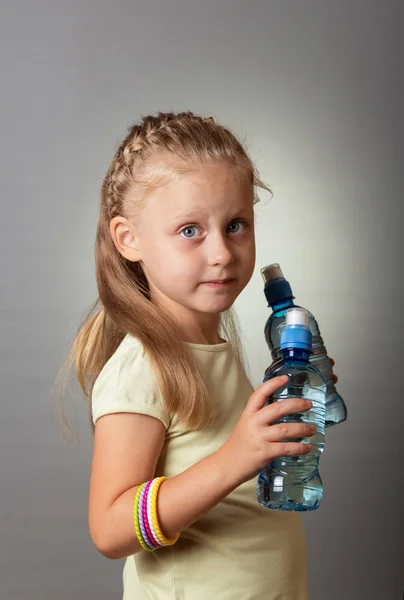 Blonde girl with water bottles on gray background — Stock Photo, Image