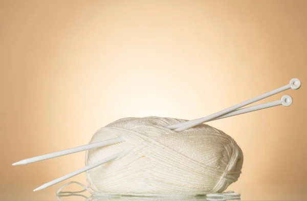 White wool skein of yarn and knitting needles on beige background — Stock Photo, Image