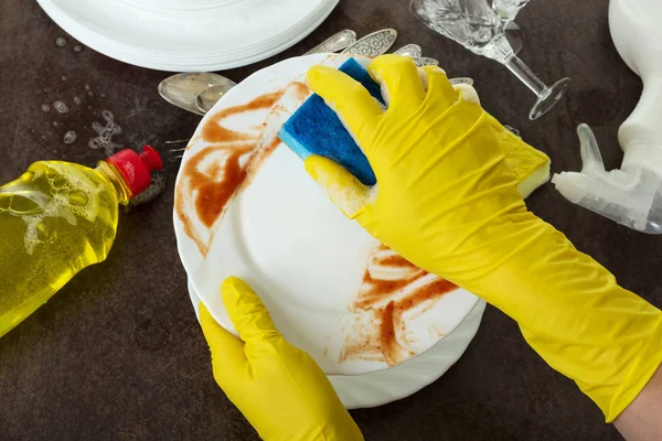 Hands in yellow gloves wash dirty dishes with sponge — 스톡 사진