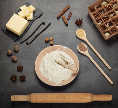 Hamur hazırlığı için gereken malzemeler, karanlık yüzeyde serili.