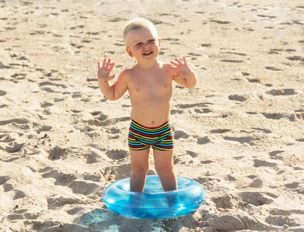 Радостный счастливый мальчик на солнечном пляже с кругом — стоковое фото
