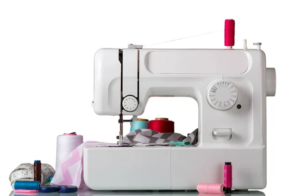 Электрическая швейная машина с аксессуарами на белом фоне — стоковое фото