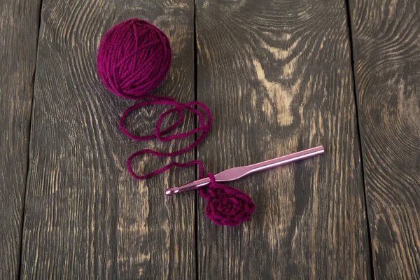 漂亮的深色木板上的紫色毛线和粉色钩子 — 图库照片
