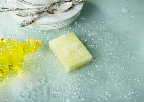 Le processus de lavage des ustensiles, des débarbouillettes et des assiettes, les moyens pour laver dans des gouttes d'eau — Photo