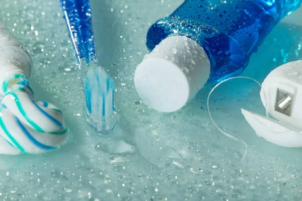 Medios para el cuidado oral y el cuidado de los dientes sobre fondo claro en gotas de agua —  Fotos de Stock