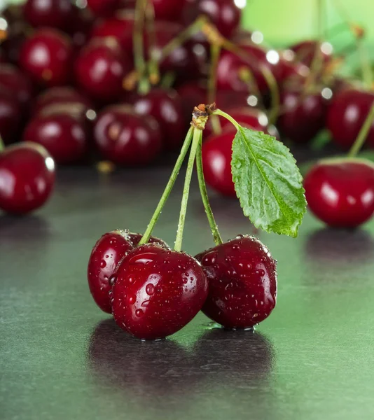 Fresh juicy cherry berries in drops of water on dark table — Stock Photo, Image