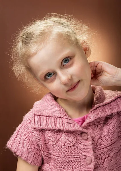 Portrait of blonde girl with pink shirt on brown background — Stock Photo, Image