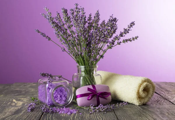 Lavendel tvål och salt, mjuk handduk och färska blommor på mörka brädor — Stockfoto