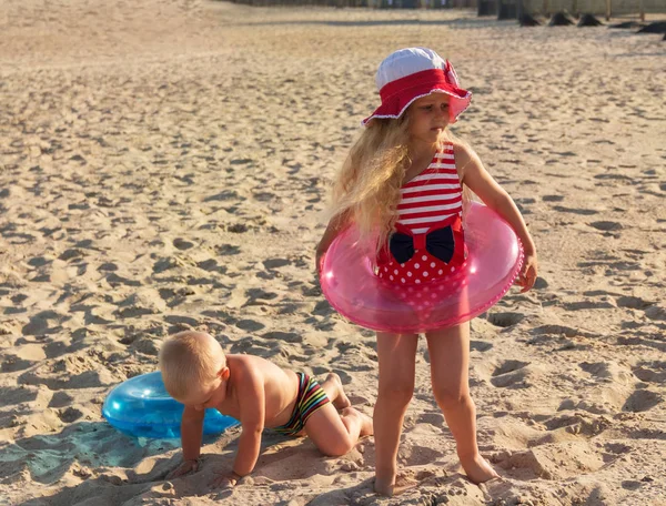 Broder og søster i cirkler til svømning leger i sand solrig strand - Stock-foto