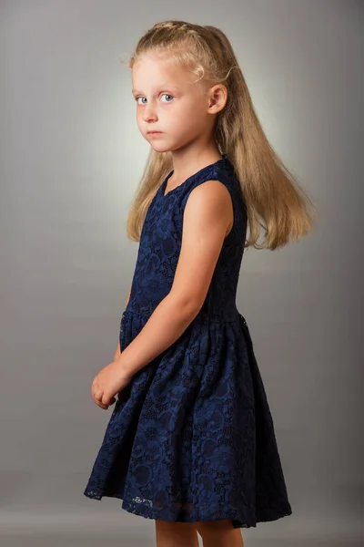 Красивая блондинка в темно-синем платье на сером фоне — стоковое фото