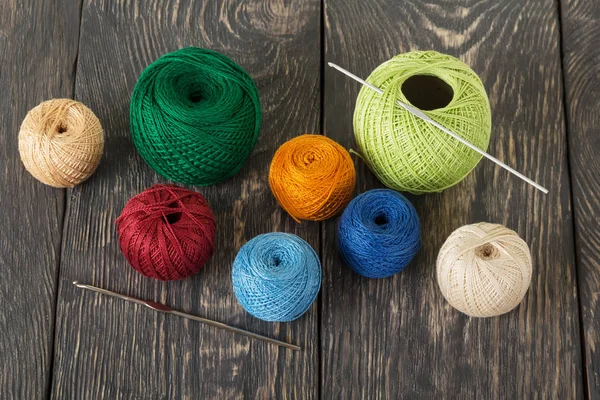 Bolas de lã multi-coloridas, ganchos de crochê em placas de madeira escura — Fotografia de Stock