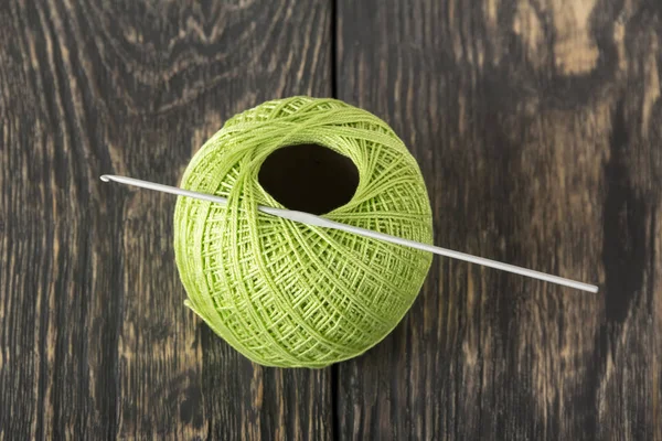 Bola de lã de cor verde e o gancho de crochê em placas escuras — Fotografia de Stock