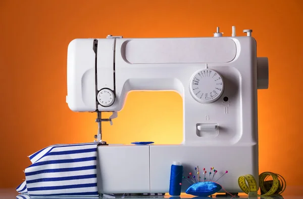 Striped dress sewing on electric sewing machine on bright yellow background — Stock Photo, Image