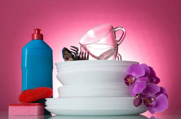 Means for washing and clean white dishes on a pink background decorated with branch of an orchid — Stock Photo, Image