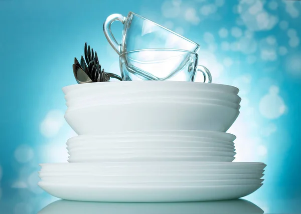 Установите чистые мытые блюда и чашки на красивом ярко-голубом фоне — стоковое фото
