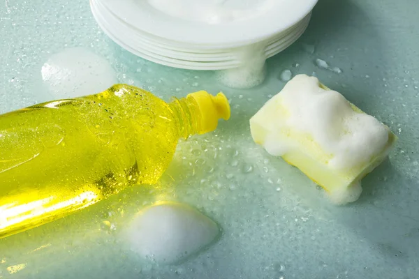 Lavagem de pratos, detergente prato, espuma e esponja amarela — Fotografia de Stock