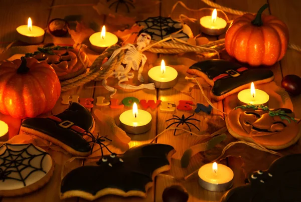 Halloween. Gâteaux d'épices de citrouille et d'araignées, bougies allumées et autres accessoires de fête sur les planches — Photo