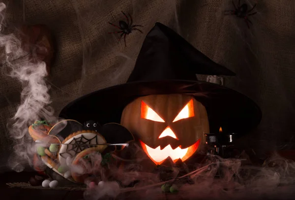 Sinister glowing Halloween pumpkin in smoke, cobweb in the background of burlap