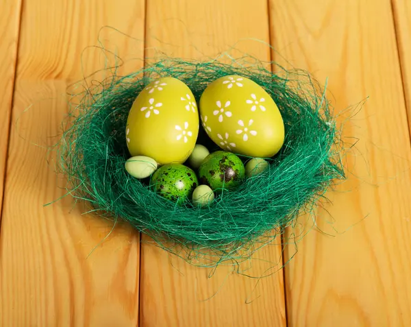 Zijn verschillende paaseieren in nest op achtergrond licht hout. — Stockfoto