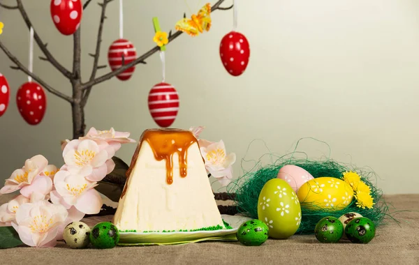 Easter eggs hanging on branches, Easter cheese dessert, flowers on gray. — Stock Photo, Image