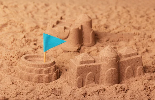 Kastelen van zand, Colosseum en blauwe vlag in zand. — Stockfoto