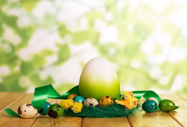 Colorful Easter eggs in nest and near, one large, ribbon. — Stock Photo, Image