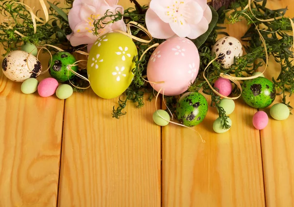 Colored Easter eggs, flowers, candy ribbon, against backdrop pal — ストック写真