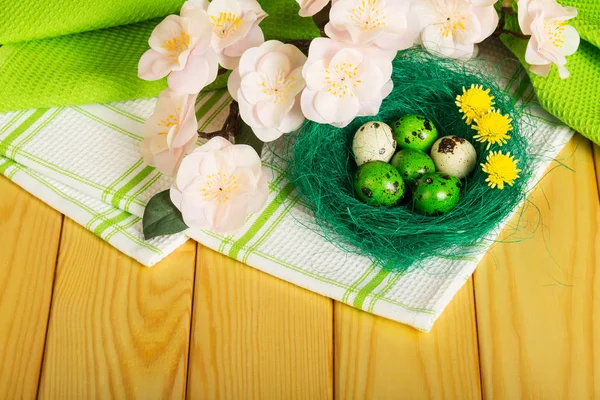 Påskägg i bo, blommor på handduk och ljust träd. — Stockfoto