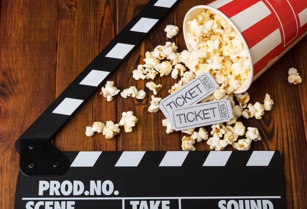 Verschüttetes Popcorn, gestreifte Schachtel, Kinokarten und Filmklöppel — Stockfoto