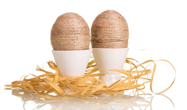 Easter eggs in cups entwined string, ribbon, isolated on white. — Stock Photo, Image