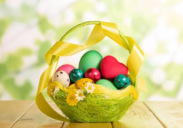 Easter eggs in basket, heart and ribbon on abstract green. — ストック写真