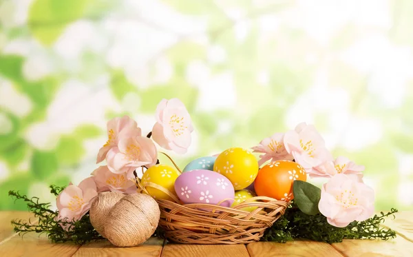 Sono diverse uova di Pasqua nel cestino e vicino, erba, fiori  . — Foto Stock