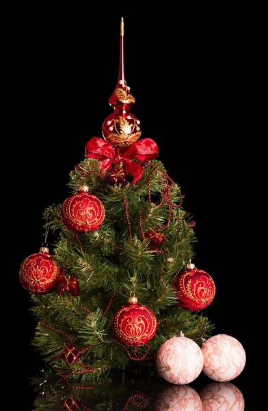 Weihnachtsbaum weihnachtlich geschmückt, neben zwei Spielzeugkugeln mit Spitze, isoliert auf schwarz — Stockfoto