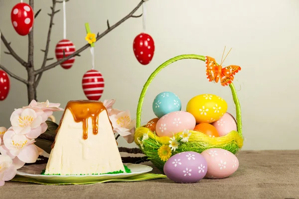 Цветные пасхальные яйца, десерт из пасхального чизкейка, цветы на сером . — стоковое фото