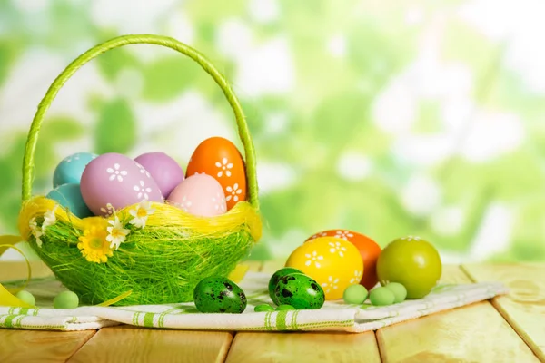 Huevos de Pascua coloridos en cesta, dulces, servilletas en verde abstracto —  Fotos de Stock
