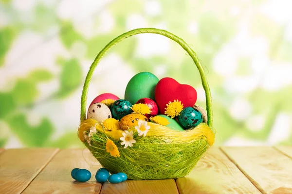 Œufs de Pâques dans le panier, coeurs rouges, fleurs et bonbons . — Photo