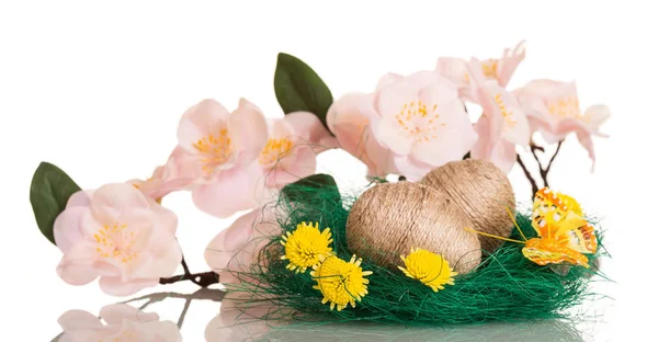 Velikonoční vajíčka v hnízdě propletená provázkem, květy, motýl — Stock fotografie